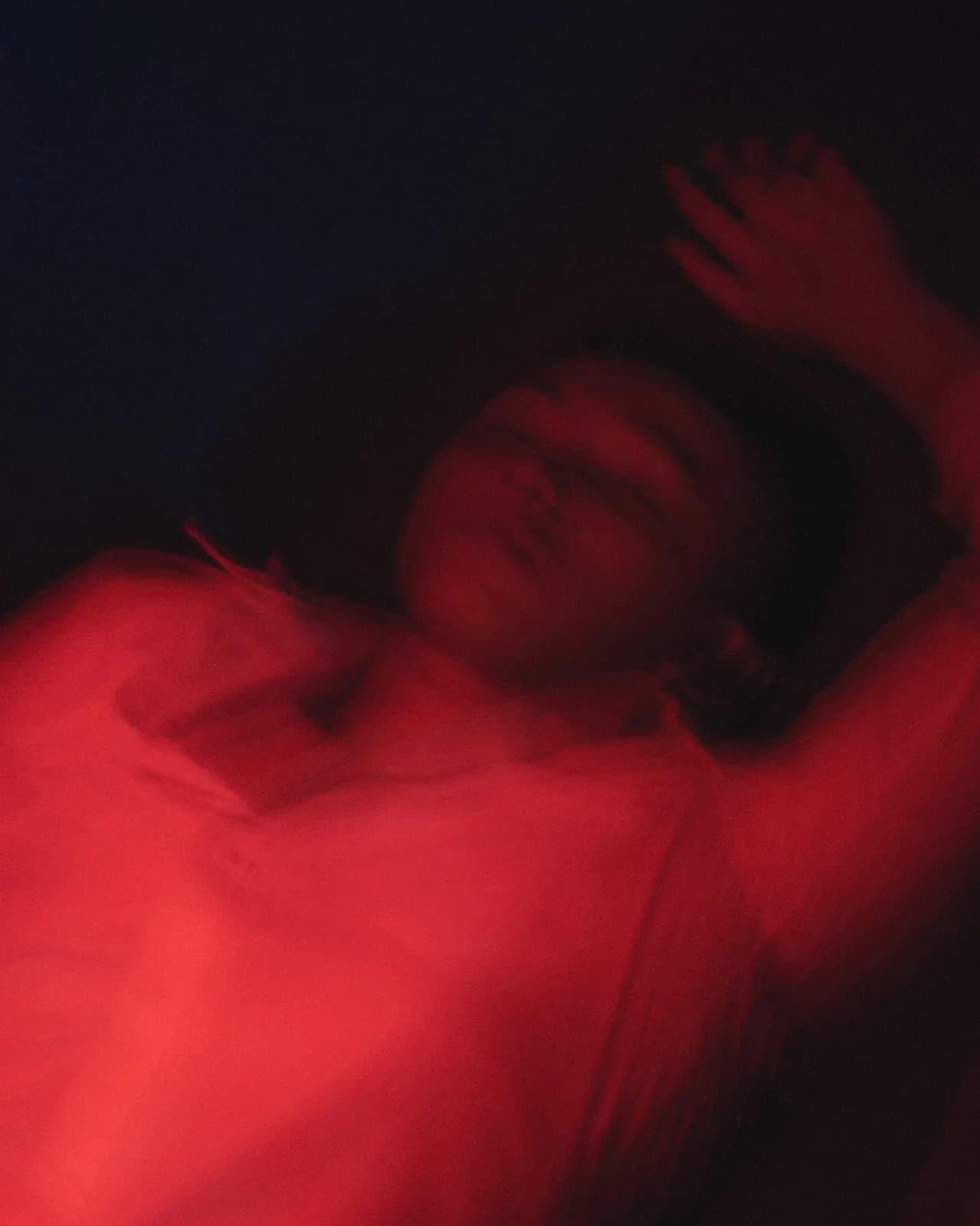 Portrait of a person reclining, bathed in deep red light