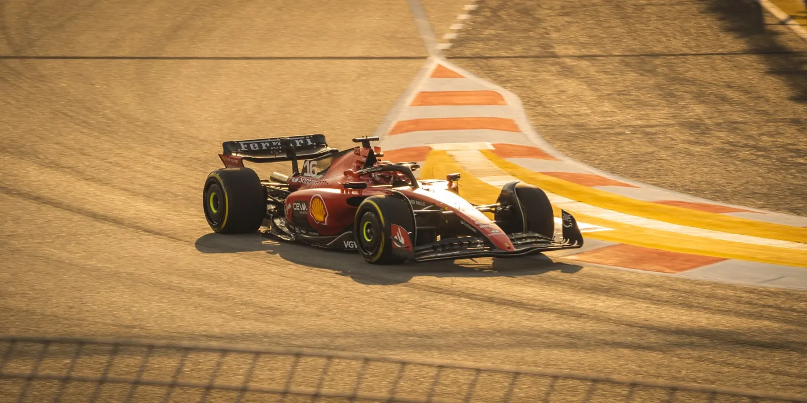 Charles Leclerc's Ferrari shot from above, crossing the striped kerb onto sand-coloured tarmac