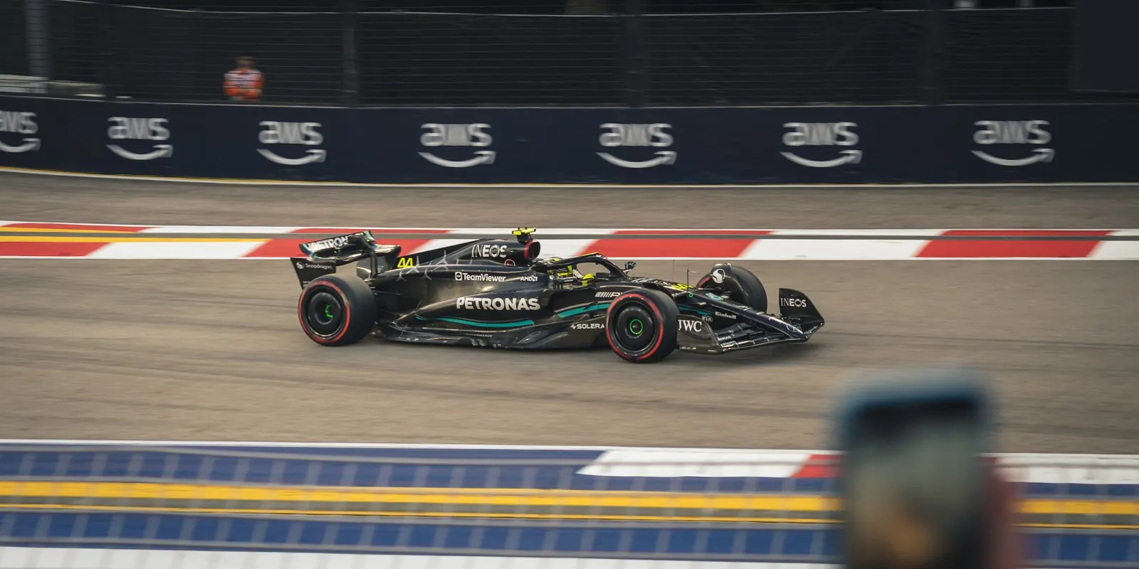 Lewis Hamilton's Mercedes at speed on a street circuit, panned against the barriers